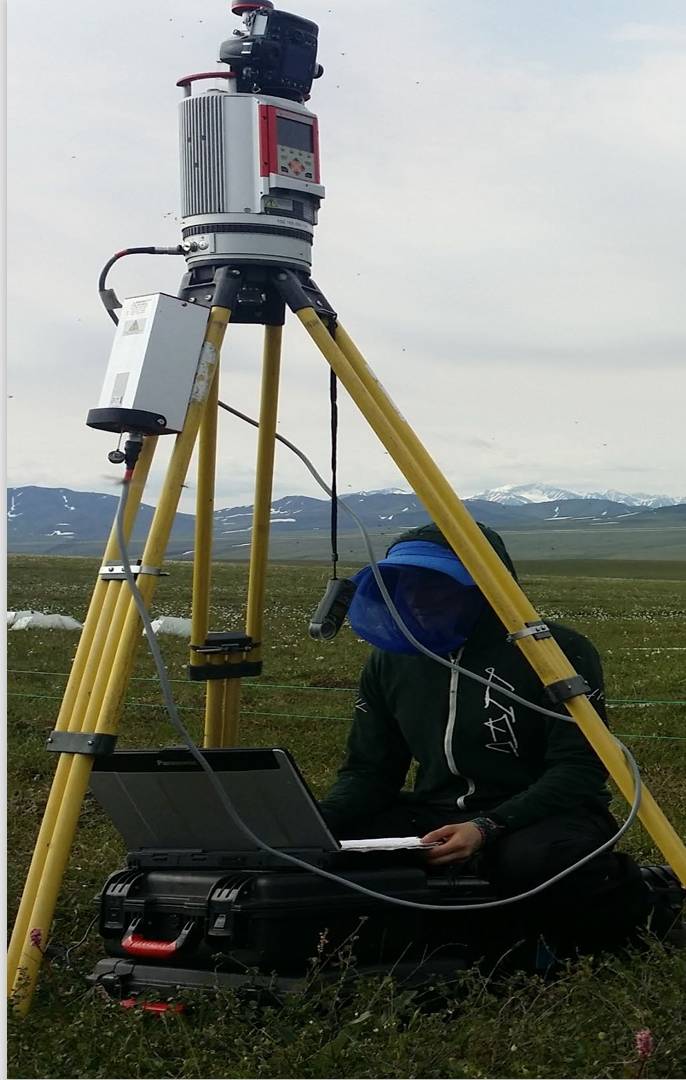A woman in a head net sitting besides a machine on tripod legs